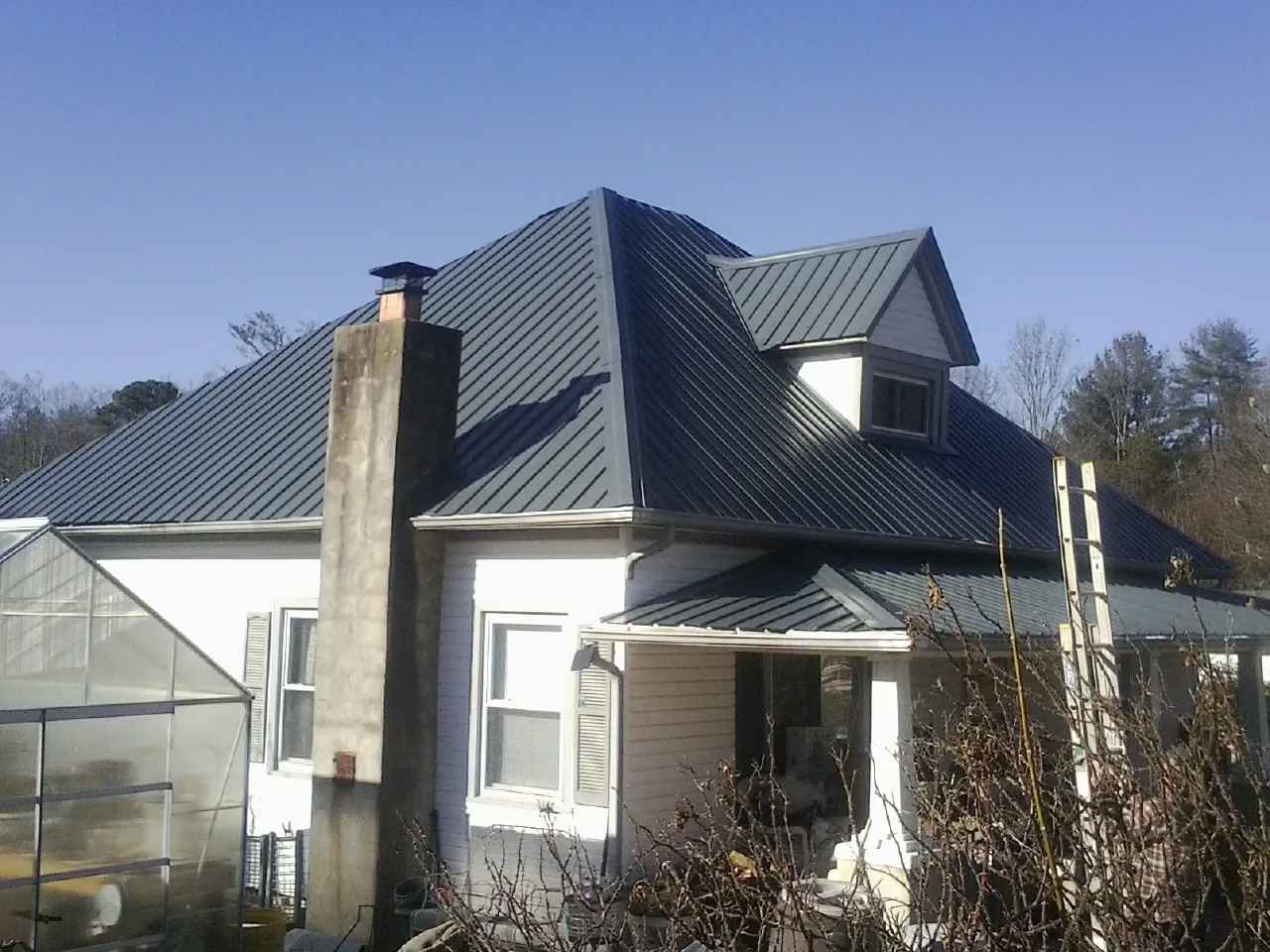 Dark blue standing seam metal roof on a white farmhouse with dormer — Slate & Tile Roof Repair by Roofing Brothers in Du Bois