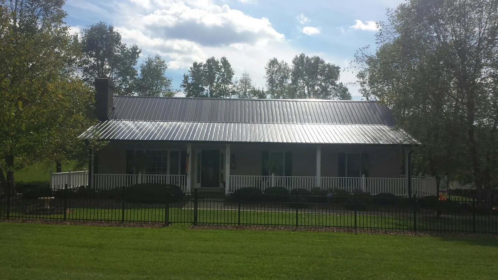 Gray metal roof on a brick ranch with a full width front porch — Gutter Guard Installation work by our crew in Du Bois