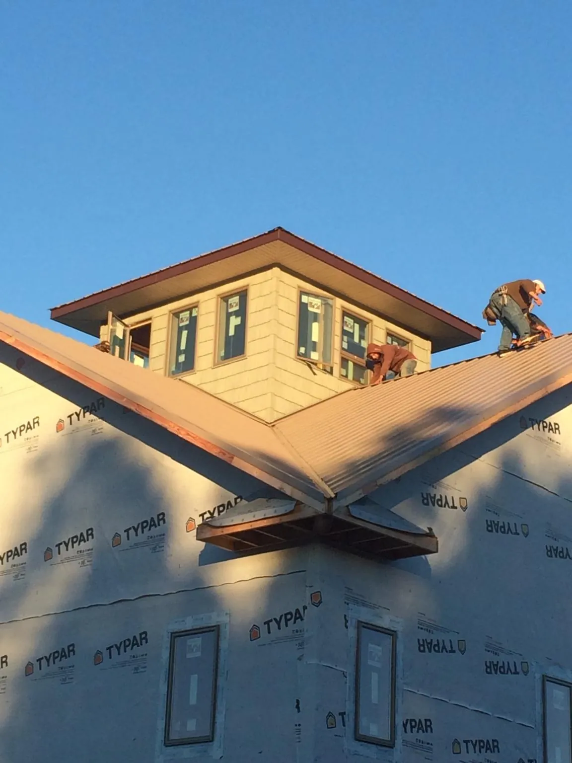 Roofers working around a rooftop cupola on a new metal roof at sunset — Roof Waterproofing in Du Bois by Roofing Brothers